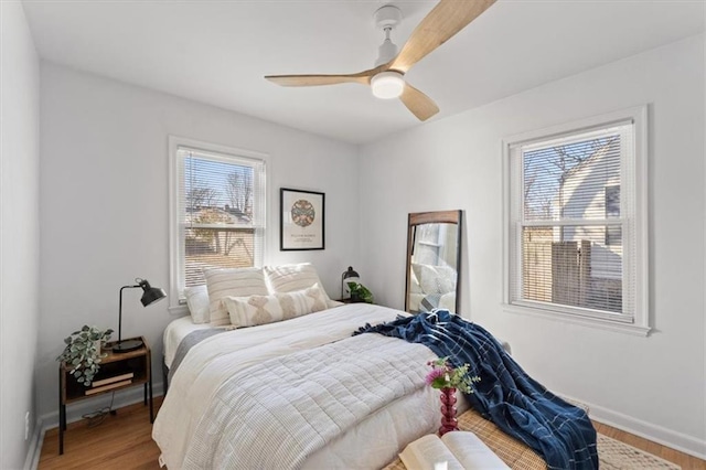 bedroom featuring hardwood / wood-style flooring, ceiling fan, and multiple windows