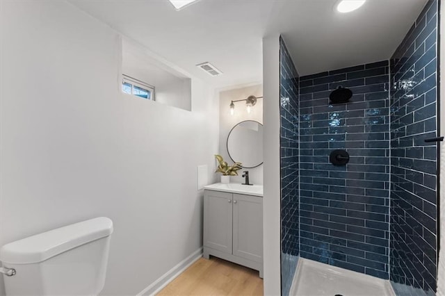 bathroom featuring vanity, wood-type flooring, toilet, and tiled shower