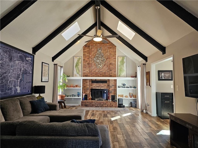 living room featuring a fireplace, a skylight, hardwood / wood-style floors, and ceiling fan