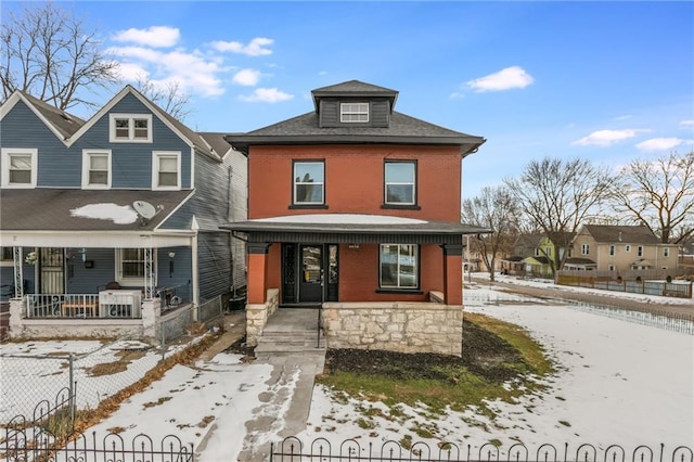 american foursquare style home with a fenced front yard, a residential view, and covered porch