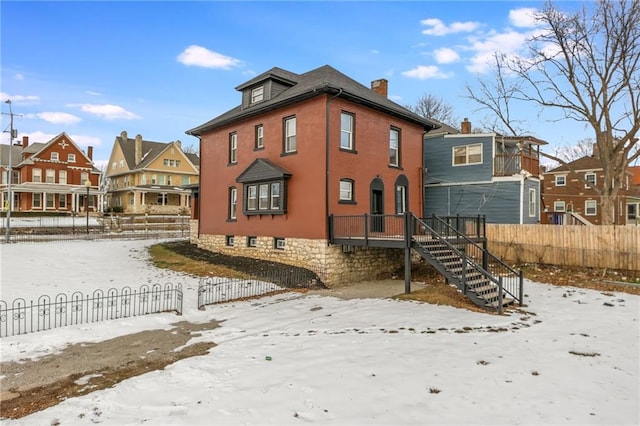 snow covered house featuring stairway, fence, and a residential view