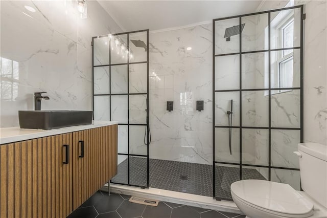 bathroom featuring tile walls, a marble finish shower, toilet, vanity, and tile patterned flooring