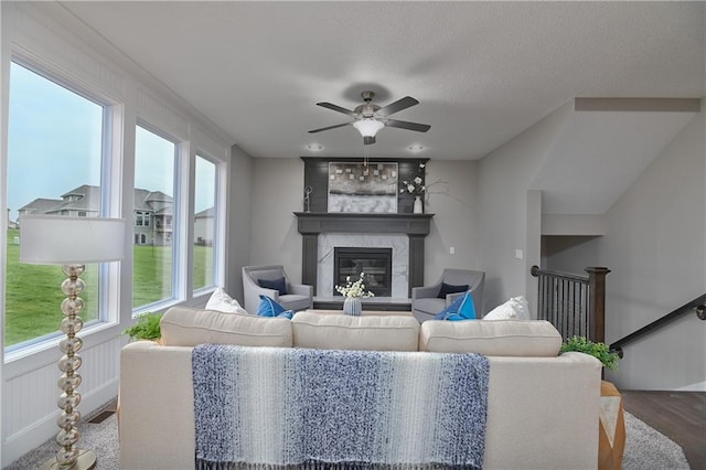 living room with ceiling fan, plenty of natural light, a fireplace, and hardwood / wood-style floors