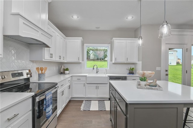 kitchen featuring pendant lighting, sink, backsplash, white cabinets, and stainless steel range with electric cooktop