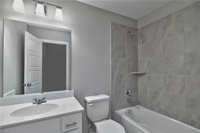 full bathroom featuring vanity, a textured ceiling, toilet, and tiled shower / bath