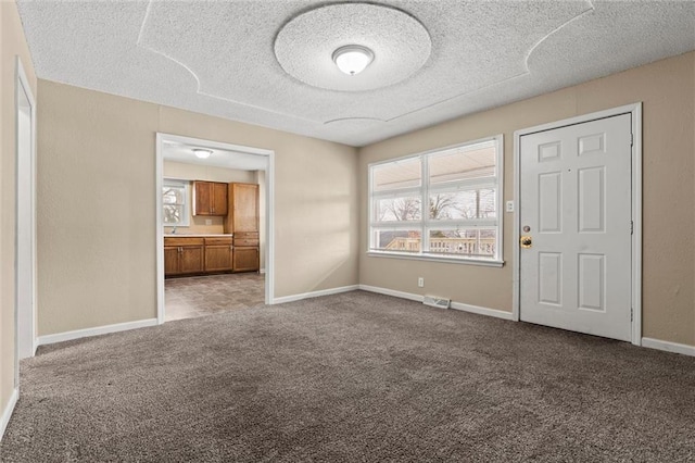 empty room with a textured ceiling and carpet flooring