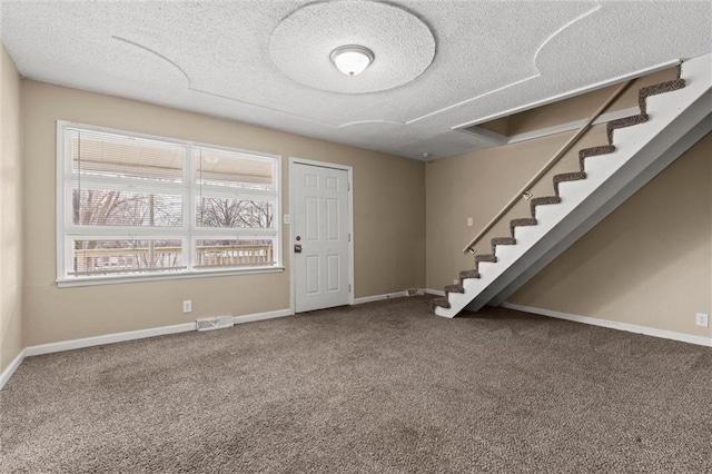 foyer entrance with carpet and a textured ceiling