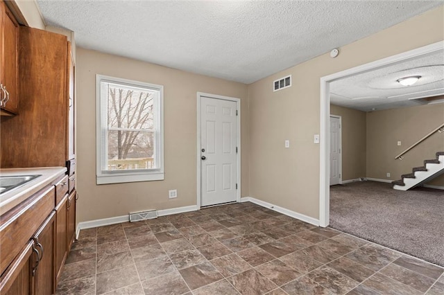 laundry area with dark colored carpet and a textured ceiling