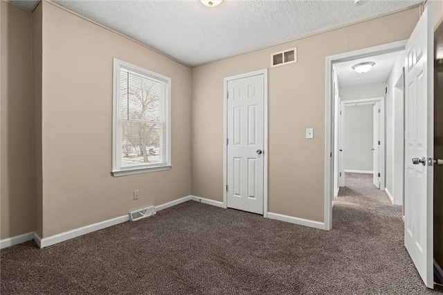 unfurnished bedroom featuring a textured ceiling and dark colored carpet