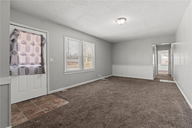 carpeted entryway featuring a healthy amount of sunlight and a textured ceiling