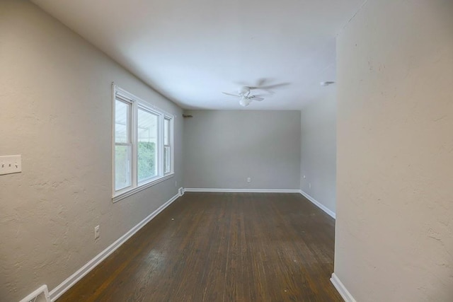 spare room featuring visible vents, baseboards, a ceiling fan, a textured wall, and dark wood-type flooring