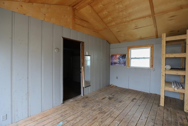 spare room with vaulted ceiling, wood-type flooring, wood ceiling, and wooden walls