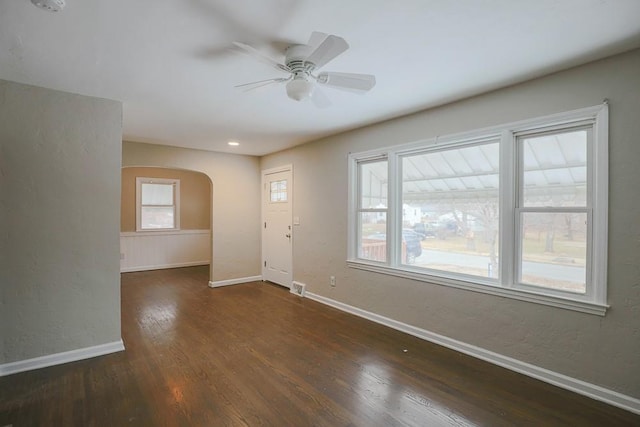 interior space with baseboards, visible vents, arched walkways, and wood finished floors