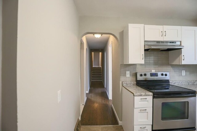 kitchen with electric stove, white cabinetry, under cabinet range hood, and decorative backsplash