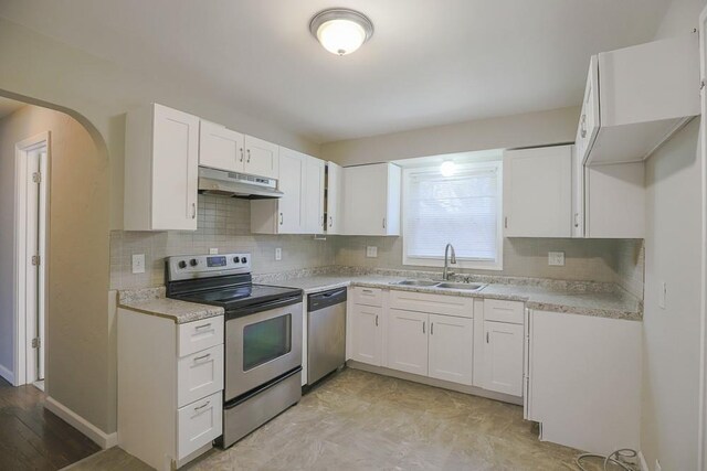 kitchen featuring under cabinet range hood, stainless steel appliances, a sink, white cabinetry, and light countertops