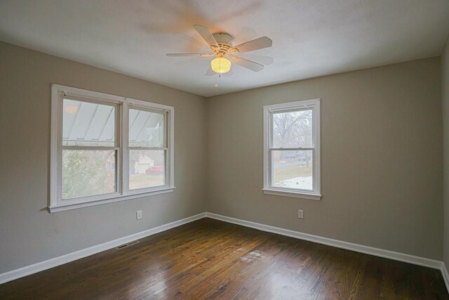 unfurnished room featuring visible vents, dark wood-type flooring, a ceiling fan, and baseboards