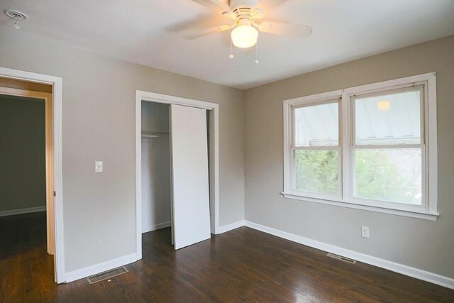 unfurnished bedroom with baseboards, visible vents, dark wood finished floors, and a closet