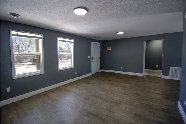 spare room featuring dark hardwood / wood-style flooring and a textured ceiling