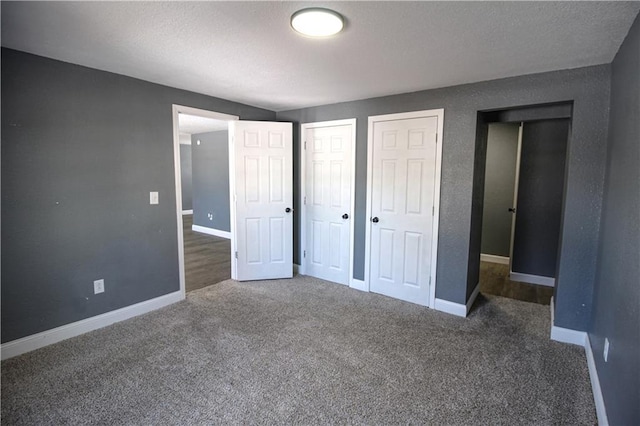 unfurnished bedroom with dark carpet and two closets