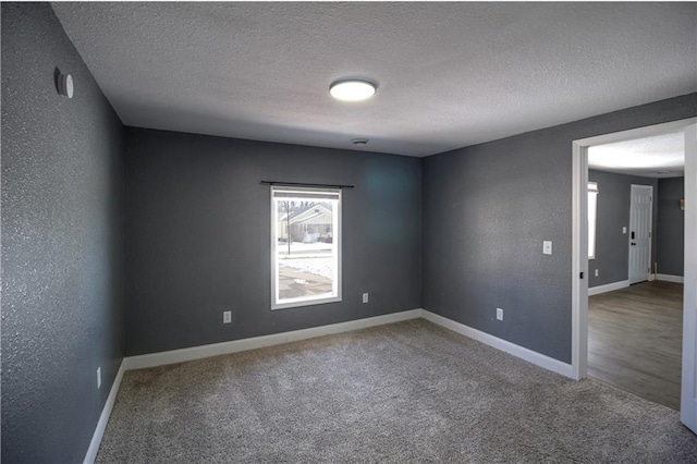 carpeted empty room featuring a textured ceiling