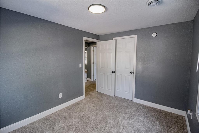 unfurnished bedroom with light colored carpet and a textured ceiling