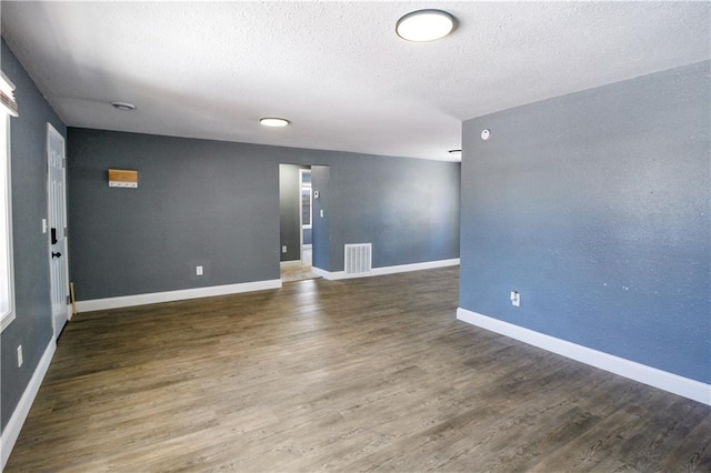 empty room with dark hardwood / wood-style floors and a textured ceiling