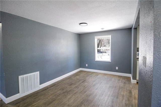 unfurnished room with dark hardwood / wood-style floors and a textured ceiling