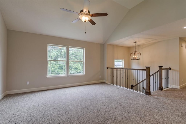 carpeted spare room with ceiling fan with notable chandelier and vaulted ceiling