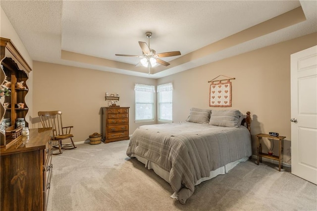 bedroom with light colored carpet, a textured ceiling, a raised ceiling, a closet, and ceiling fan