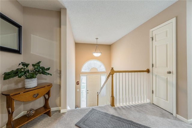 carpeted foyer entrance with a textured ceiling