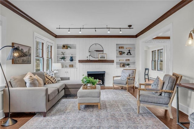 living room featuring crown molding, a brick fireplace, hardwood / wood-style flooring, and built in features