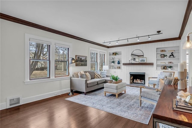 living room featuring built in shelves, crown molding, and dark hardwood / wood-style flooring