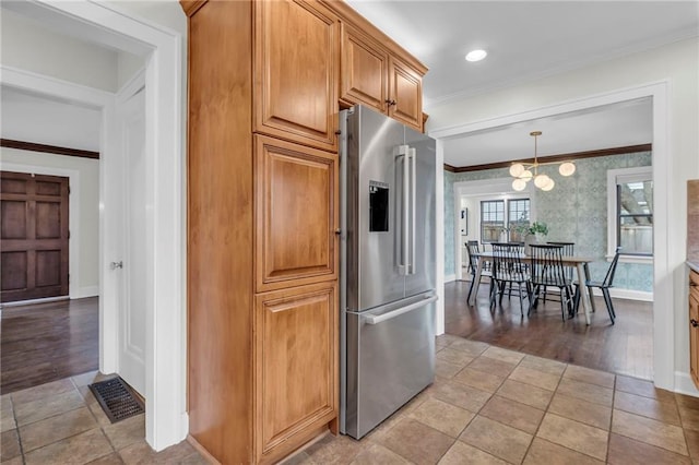 kitchen with hanging light fixtures, crown molding, high end refrigerator, and light tile patterned floors