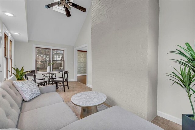 living room featuring ceiling fan, brick wall, and high vaulted ceiling