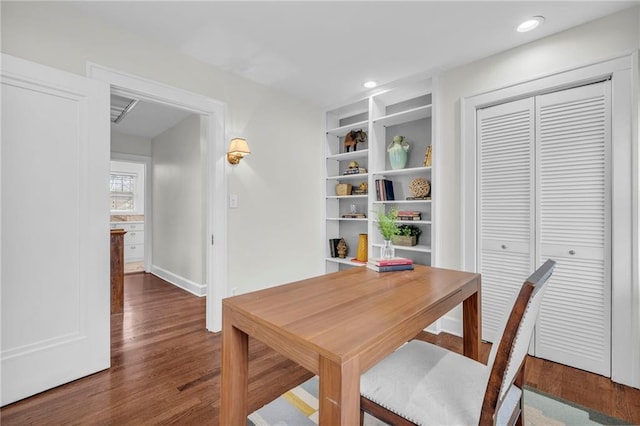 office space with dark hardwood / wood-style floors and built in shelves