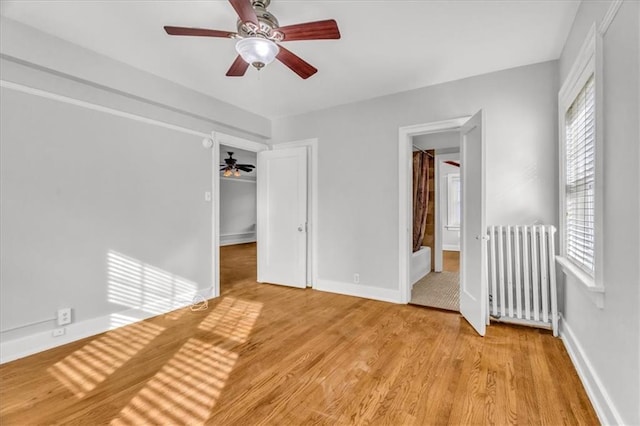 unfurnished bedroom featuring ceiling fan, radiator heating unit, and light wood-type flooring