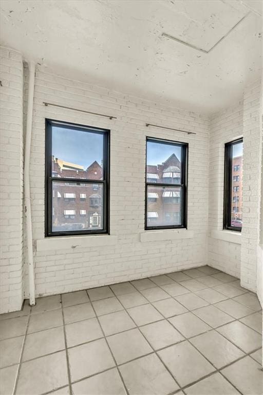 spare room with brick wall and light tile patterned floors