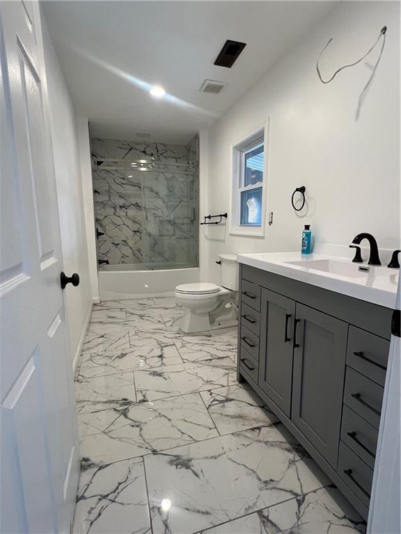 full bathroom with vanity, tiled shower / bath combo, and toilet