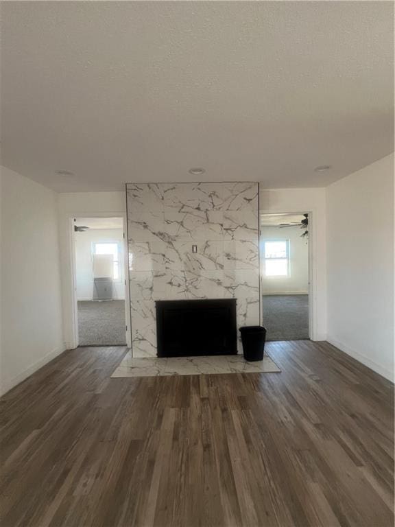 unfurnished living room with dark hardwood / wood-style flooring, a high end fireplace, and a textured ceiling