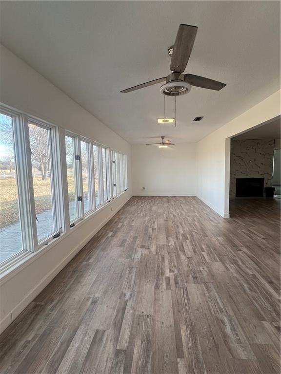 unfurnished living room with a healthy amount of sunlight, hardwood / wood-style floors, and ceiling fan