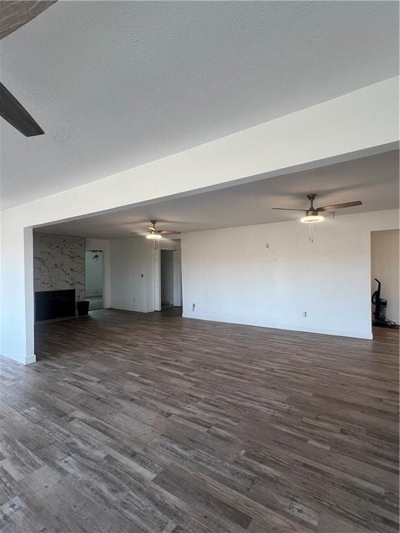 unfurnished living room with dark wood-type flooring, ceiling fan, and a textured ceiling