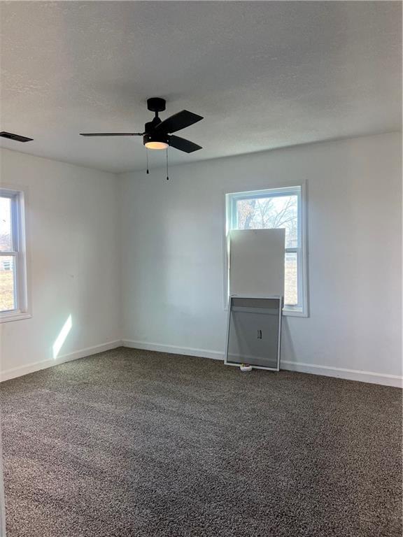 carpeted empty room with a textured ceiling and ceiling fan