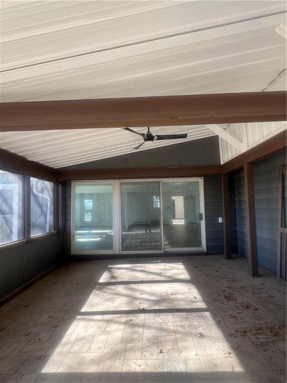 unfurnished sunroom featuring vaulted ceiling with beams