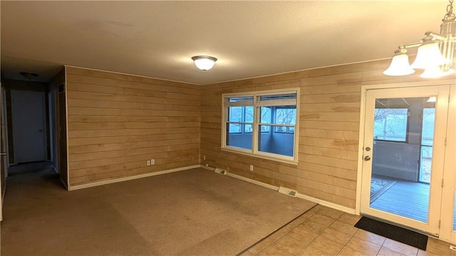 empty room with a wealth of natural light, a chandelier, and wood walls