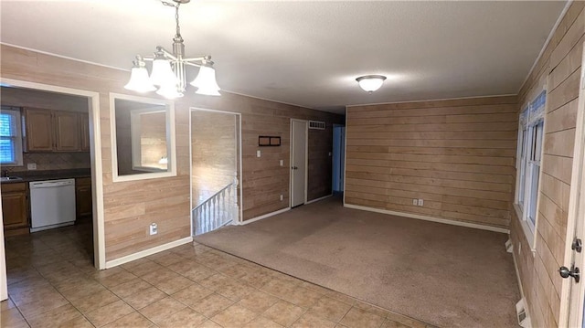 spare room with carpet flooring, a chandelier, sink, and wood walls