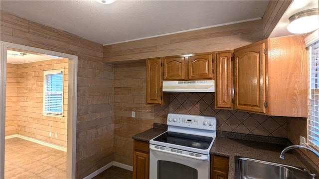 kitchen with sink, electric range, backsplash, and wood walls