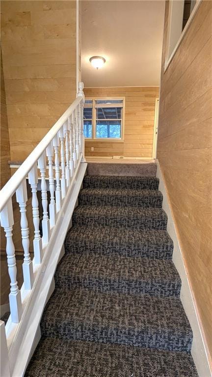 stairway with carpet and wood walls