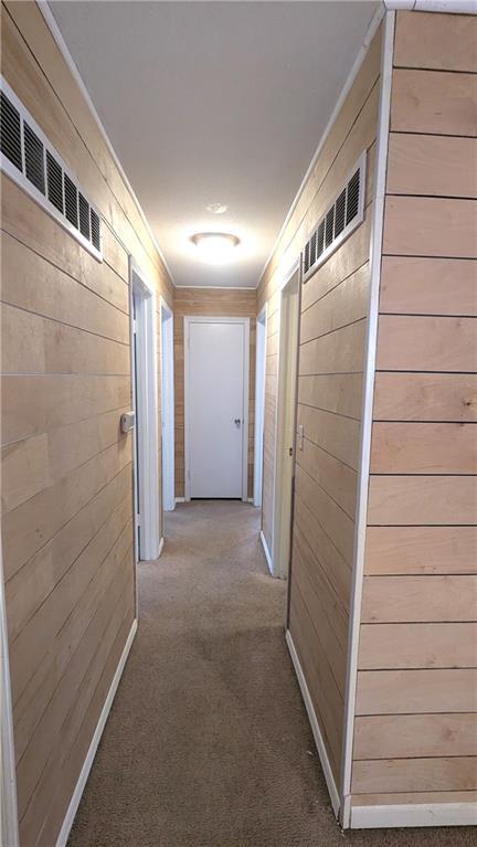 hallway with crown molding, carpet, and wooden walls