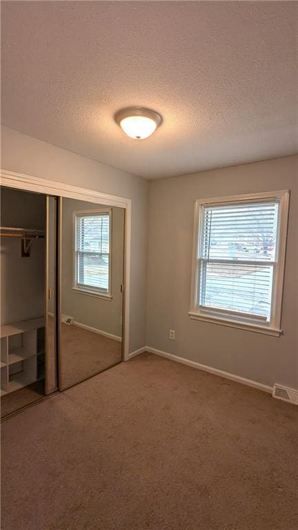 unfurnished bedroom with multiple windows, carpet flooring, and a closet