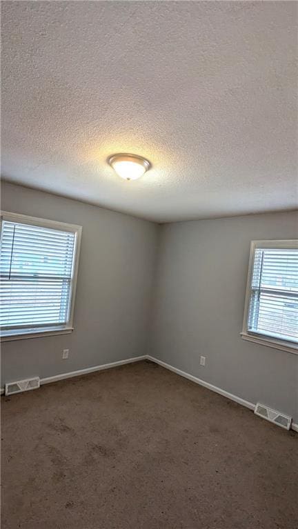 carpeted empty room featuring a textured ceiling